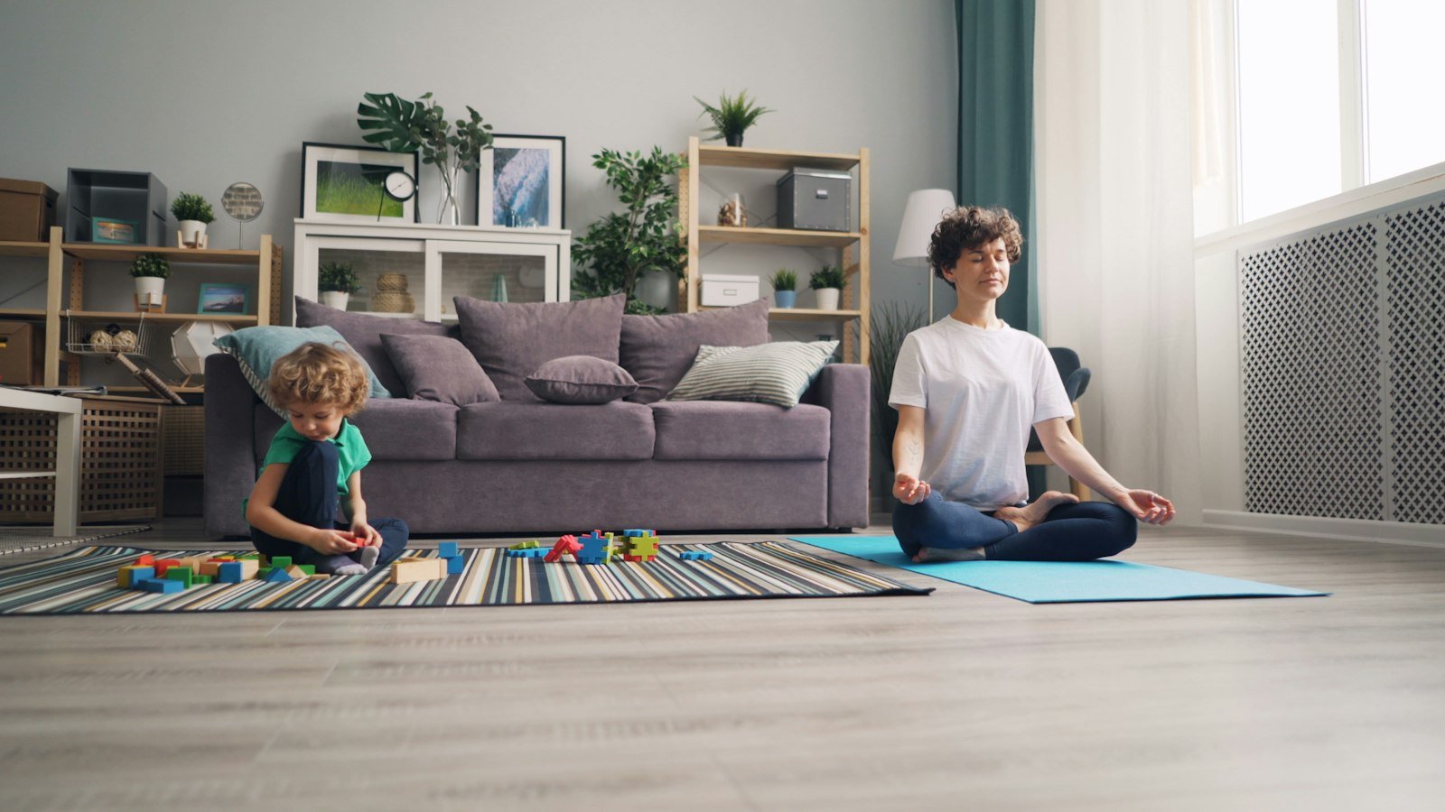 A mother and child sitting cross-legged on a rug, breathing together