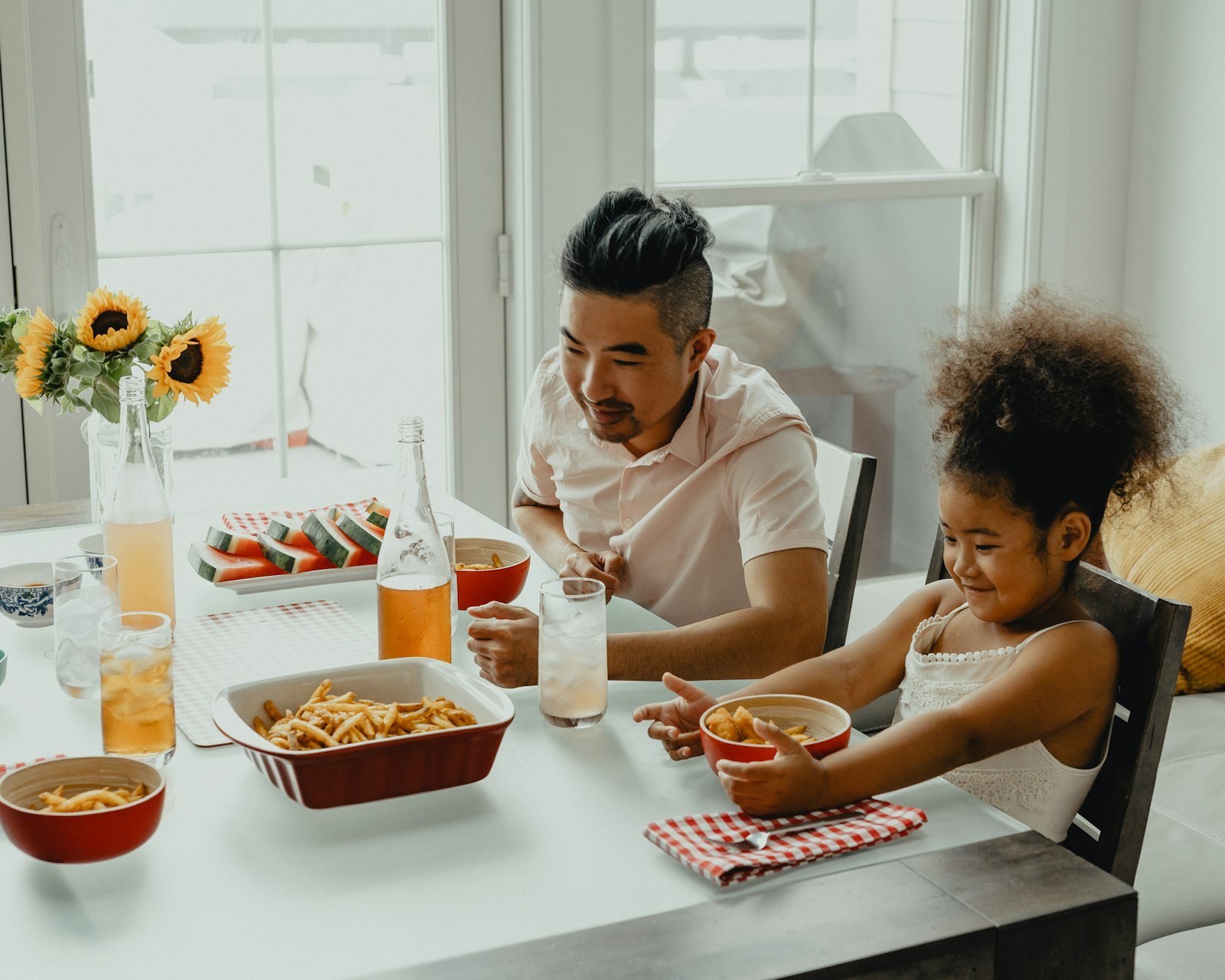 A father and his daughter sharing a meal at a bright kitchen table