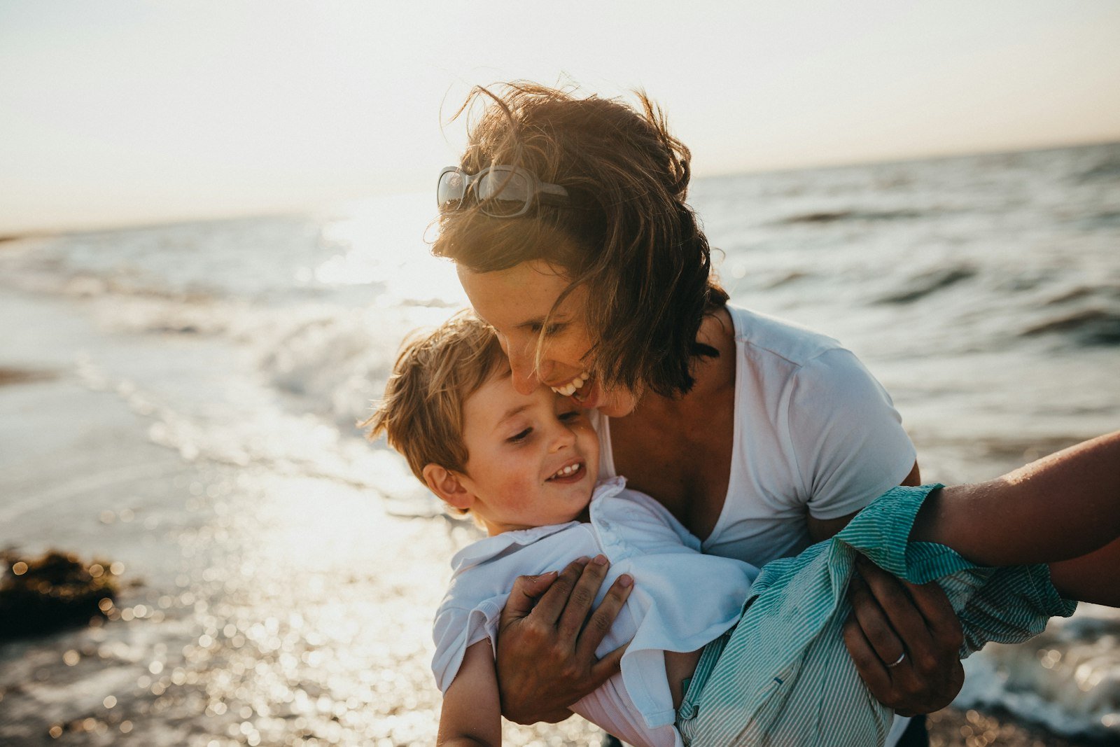 A mother and her young son sitting together by the water