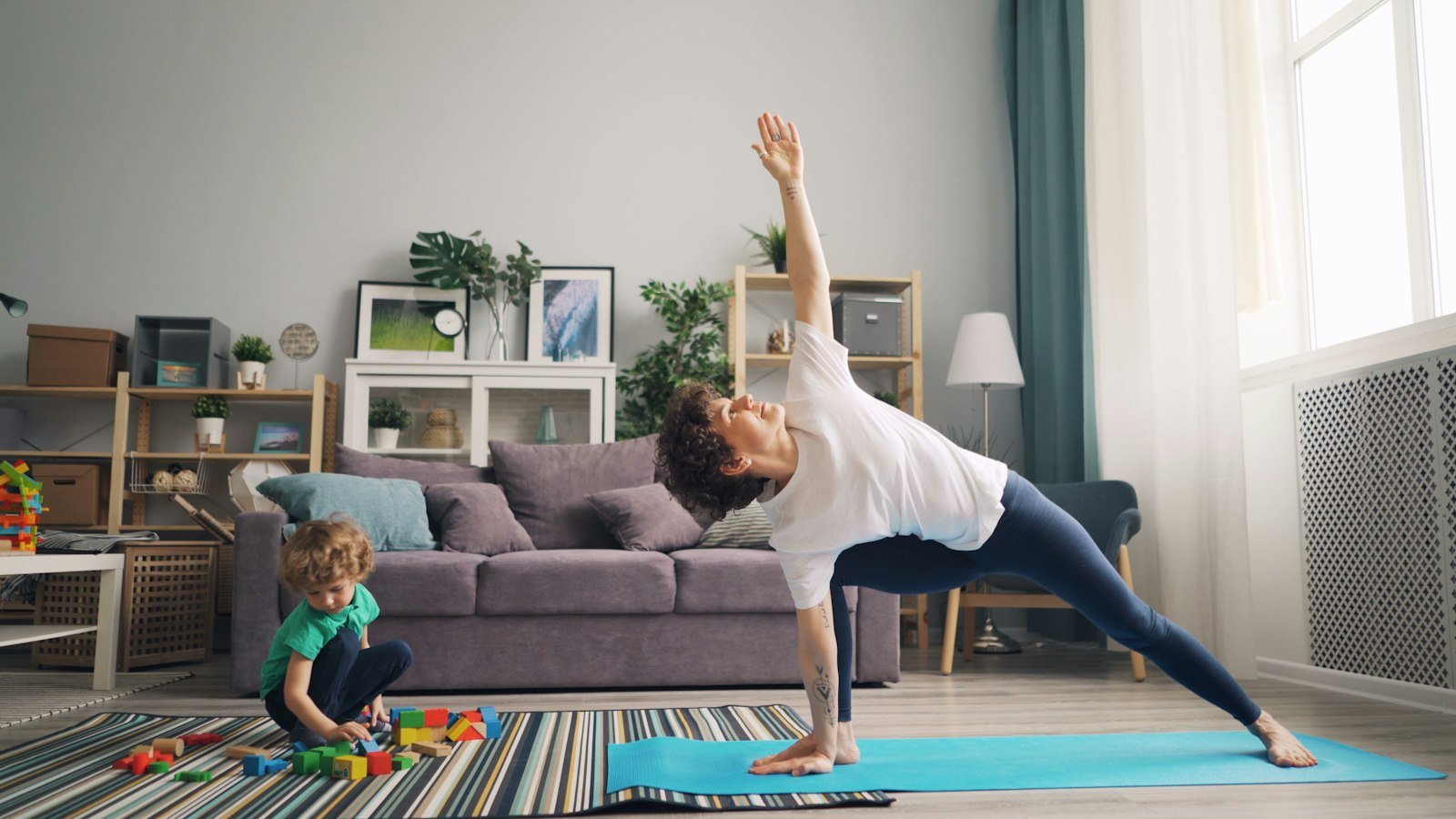 A mother and child practicing a yoga pose together in the living room