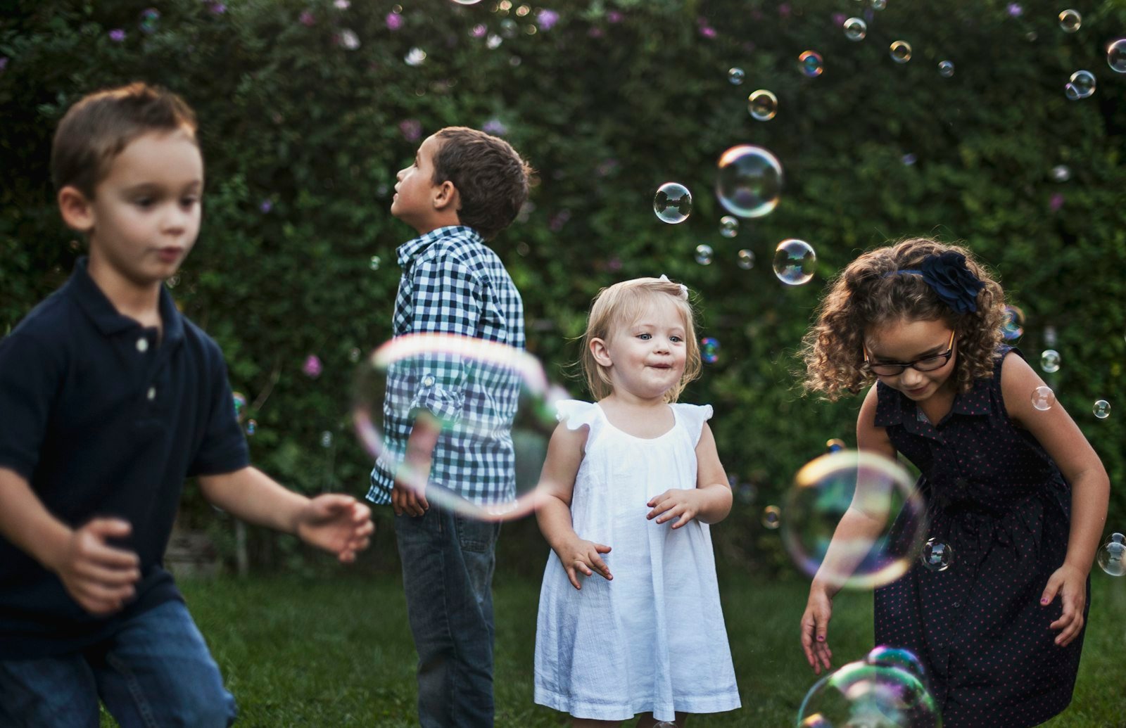 Children playing with floating bubbles in a green garden